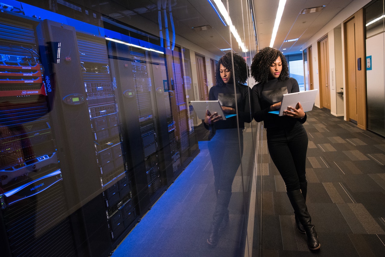 A woman engineer holding a laptop in front of a data center